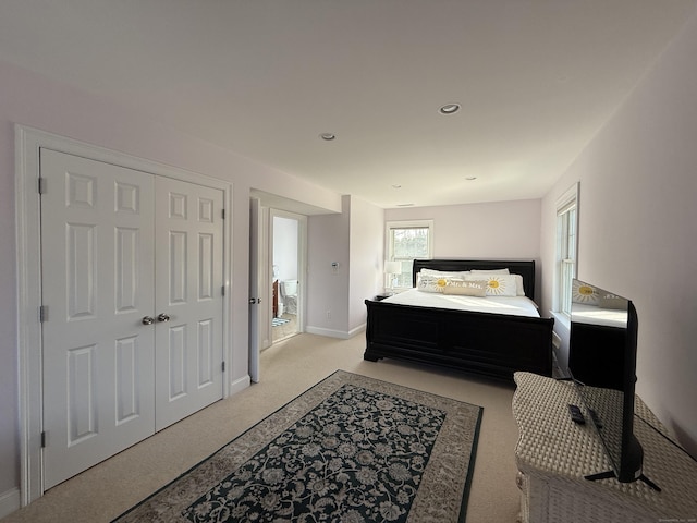 bedroom with light carpet, a closet, recessed lighting, and baseboards