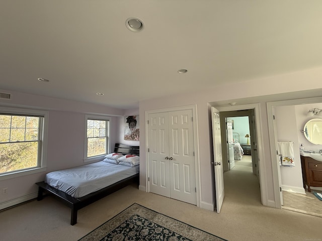 bedroom featuring light carpet, visible vents, baseboards, a baseboard radiator, and a closet