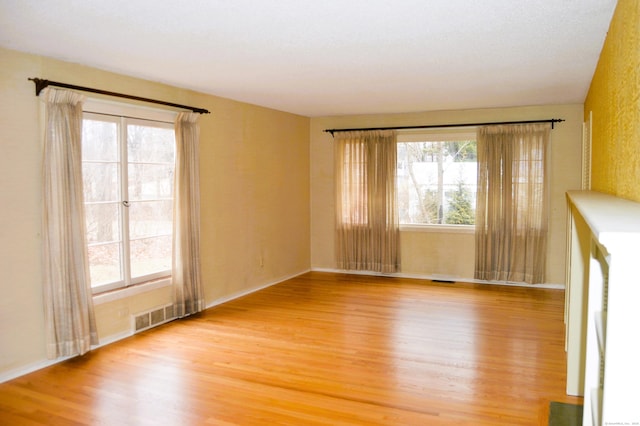 spare room with visible vents, plenty of natural light, and light wood-style flooring