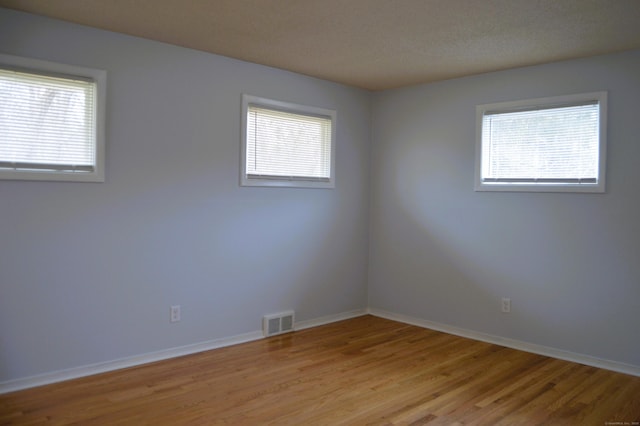 spare room with a healthy amount of sunlight, visible vents, light wood-style flooring, and baseboards