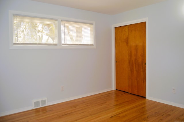 empty room featuring wood finished floors, visible vents, and baseboards