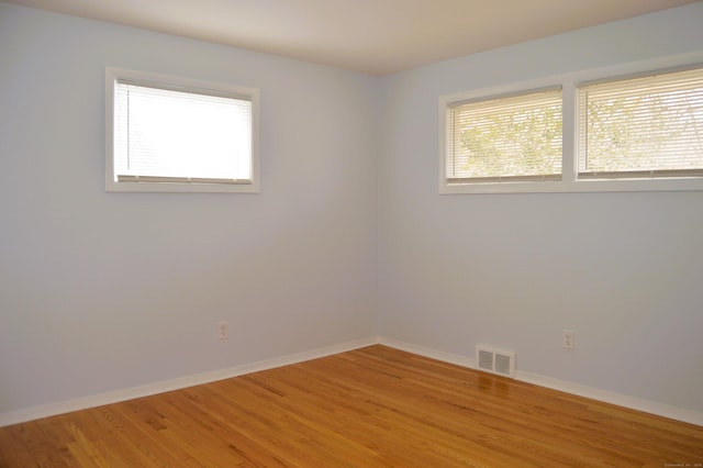 empty room with light wood-style floors, baseboards, and visible vents