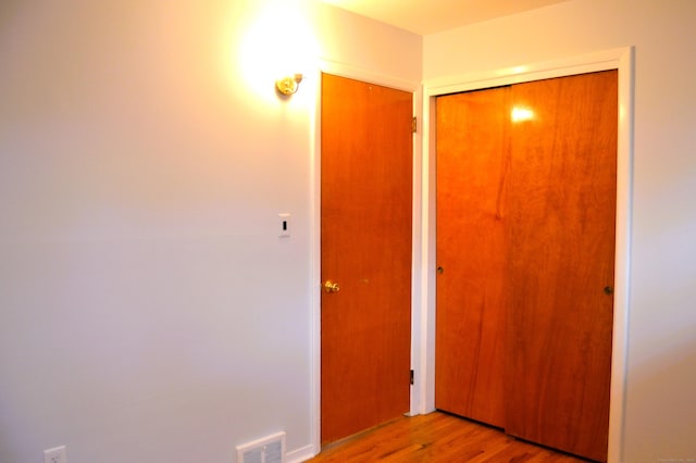 hallway featuring visible vents and wood finished floors