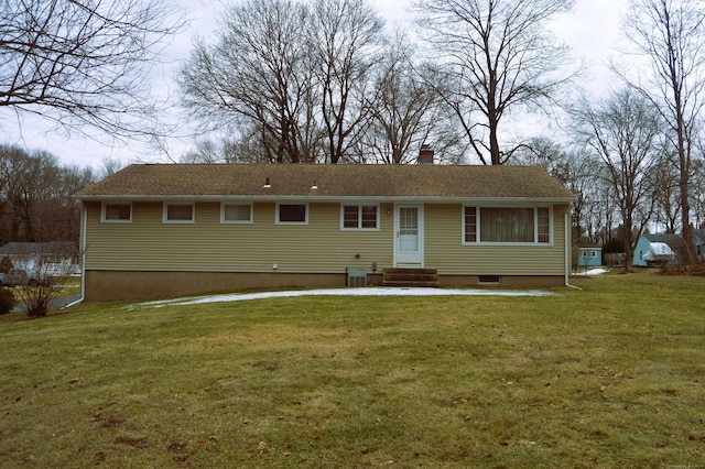 back of house with entry steps, a chimney, and a lawn