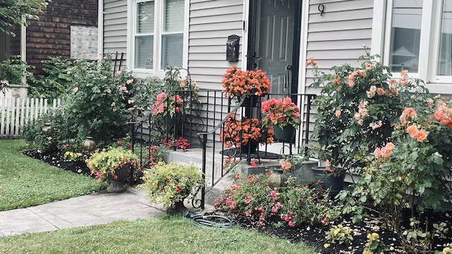 doorway to property with a lawn and fence