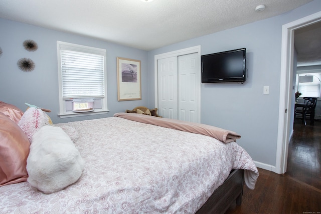 bedroom featuring dark wood-style floors, a closet, a textured ceiling, and baseboards