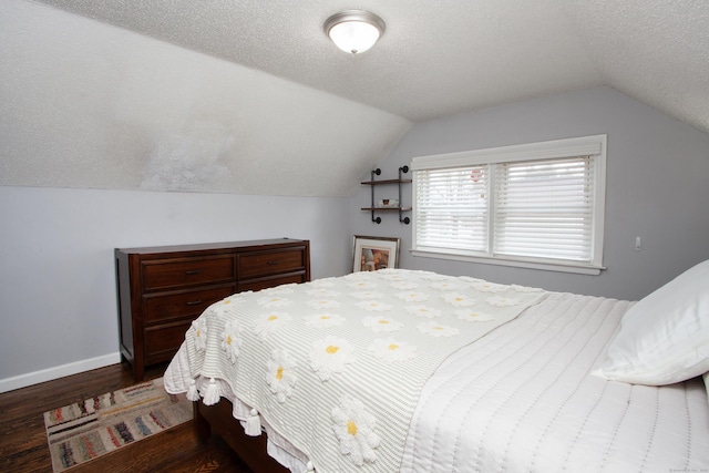 bedroom with lofted ceiling, a textured ceiling, baseboards, and wood finished floors