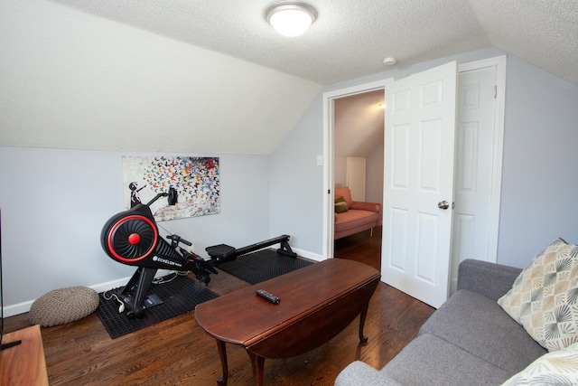 exercise area with a textured ceiling, wood finished floors, lofted ceiling, and baseboards