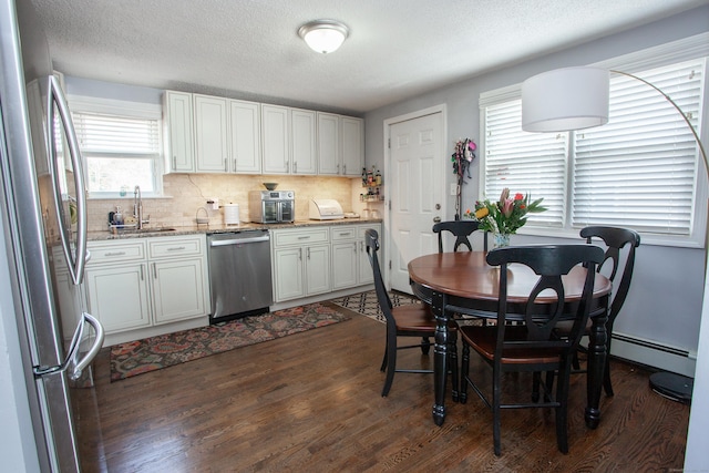 kitchen with stainless steel appliances, dark wood-type flooring, a sink, and decorative backsplash