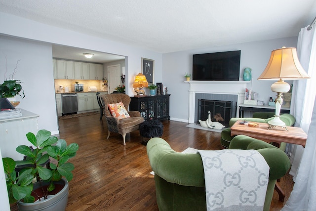 living area with dark wood-style floors, a tile fireplace, and baseboards