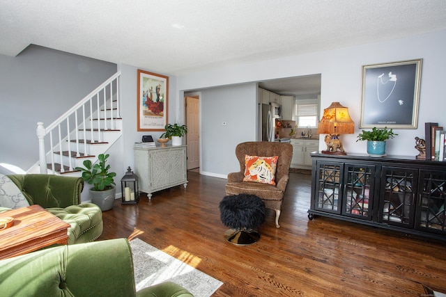 living area featuring a textured ceiling, stairway, and wood finished floors