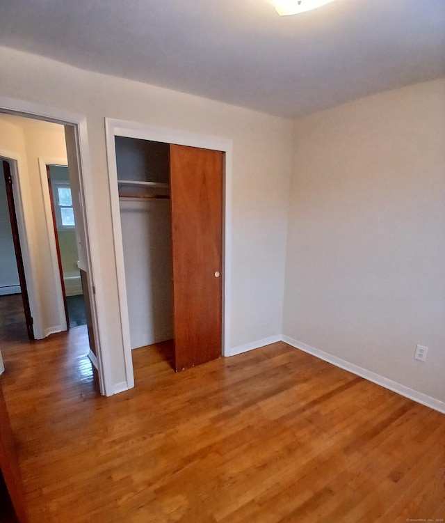 unfurnished bedroom with light wood-style flooring, baseboards, and a closet