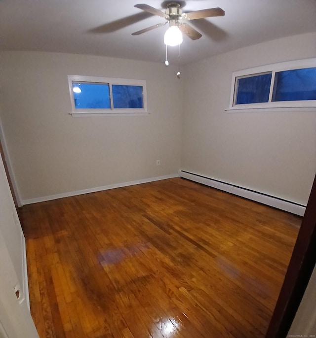 spare room with hardwood / wood-style floors, baseboard heating, a ceiling fan, and baseboards