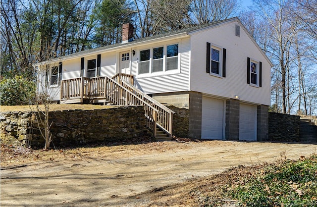 ranch-style house with a garage, dirt driveway, and a chimney