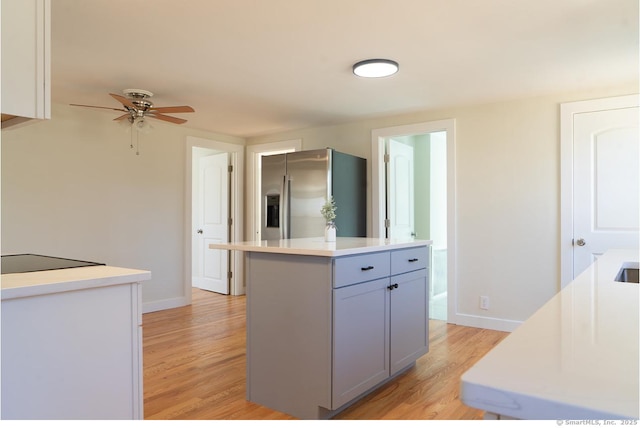 kitchen with light countertops, light wood-type flooring, black electric cooktop, and stainless steel fridge with ice dispenser