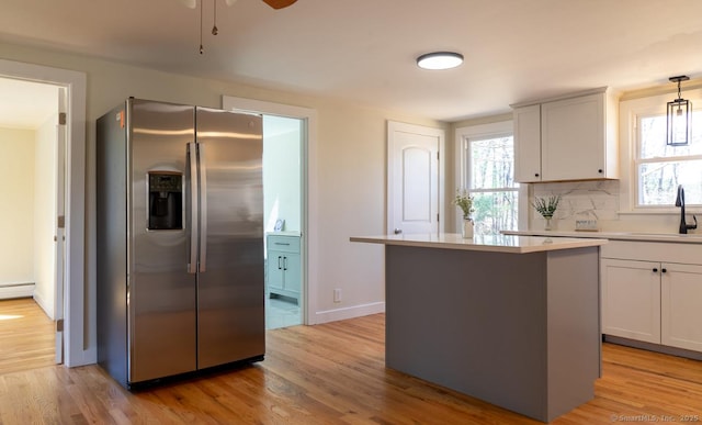 kitchen with backsplash, a sink, light wood-style flooring, and stainless steel fridge with ice dispenser