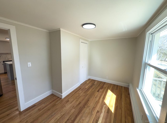 spare room featuring wood finished floors, baseboards, and ornamental molding