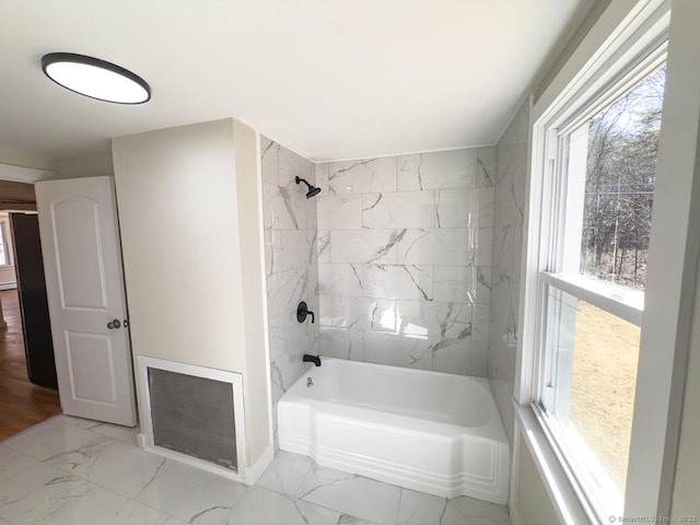 full bath featuring marble finish floor and washtub / shower combination