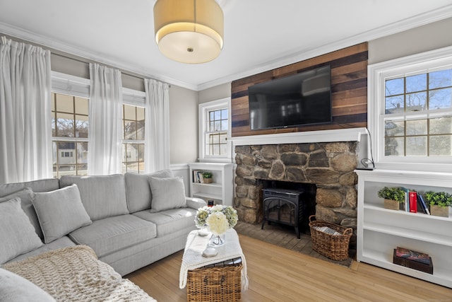 living room with crown molding, a wood stove, and wood finished floors