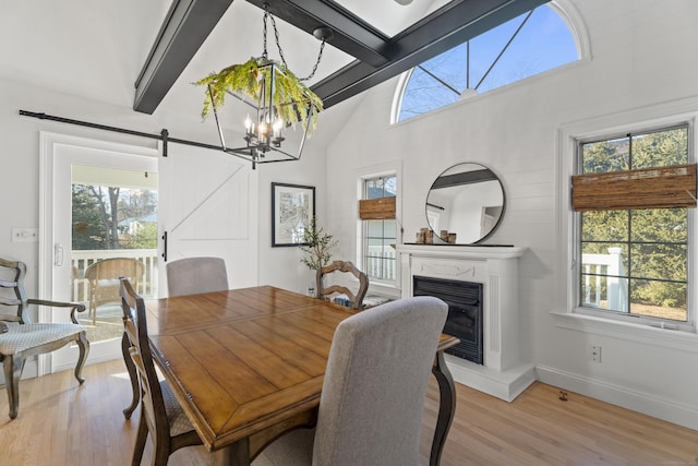 dining space featuring light wood-type flooring, plenty of natural light, and a barn door