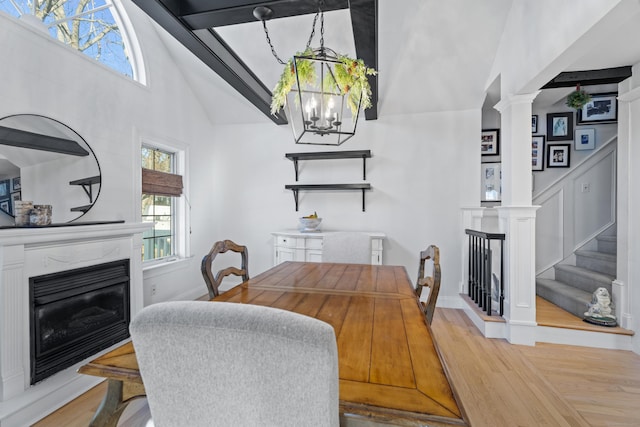 dining room featuring a glass covered fireplace, a notable chandelier, wood finished floors, and stairs