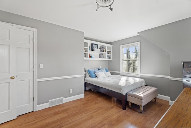 bedroom with visible vents, baseboards, and wood finished floors