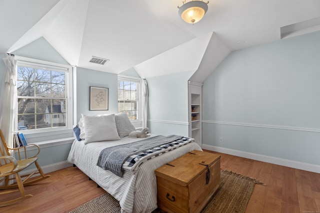 bedroom featuring visible vents, baseboards, wood finished floors, and vaulted ceiling