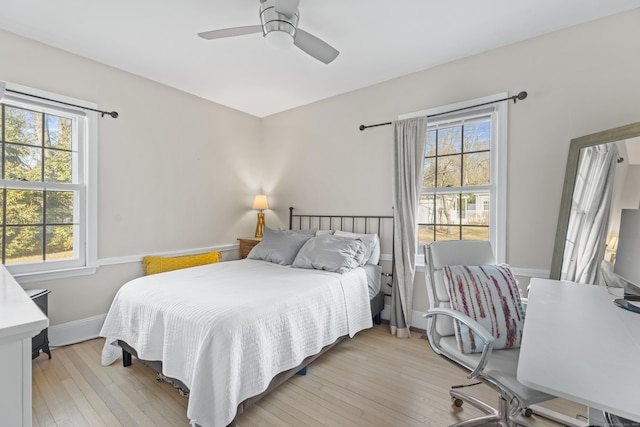 bedroom featuring baseboards, multiple windows, and light wood-style floors