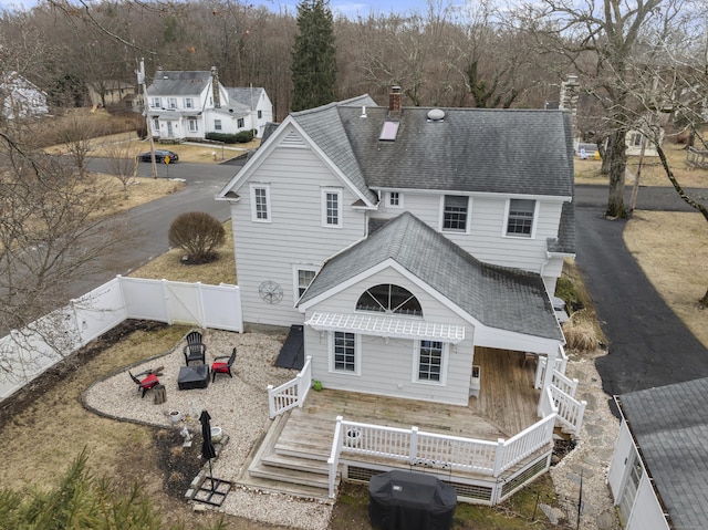 back of property with a wooden deck, a fenced backyard, a chimney, and a shingled roof