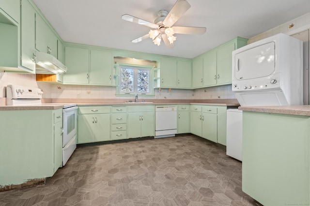 kitchen featuring under cabinet range hood, a sink, tasteful backsplash, stacked washing maching and dryer, and white appliances