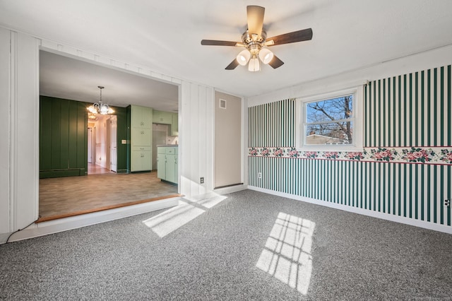 empty room featuring ceiling fan with notable chandelier and baseboards