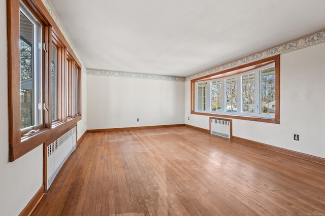 spare room featuring hardwood / wood-style floors, radiator, and a wealth of natural light