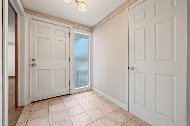 foyer entrance with light tile patterned floors, baseboards, and wallpapered walls