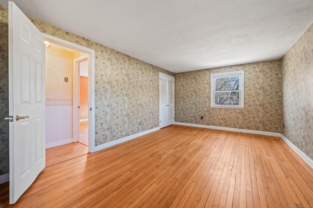 spare room with baseboards, light wood-style flooring, and wallpapered walls