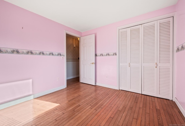 unfurnished bedroom featuring a closet, baseboards, and light wood-style flooring