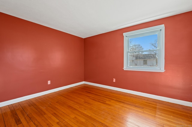 spare room featuring baseboards and hardwood / wood-style flooring