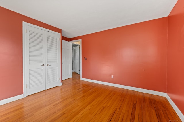 unfurnished bedroom featuring a closet, light wood-type flooring, and baseboards