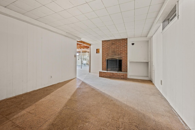 unfurnished living room with tile patterned floors, a brick fireplace, and wooden walls