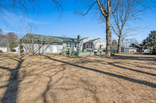 rear view of property with a yard, a chimney, and a wooden deck