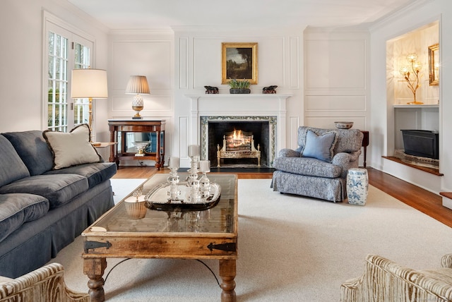 living room with crown molding, wood finished floors, a decorative wall, and a premium fireplace