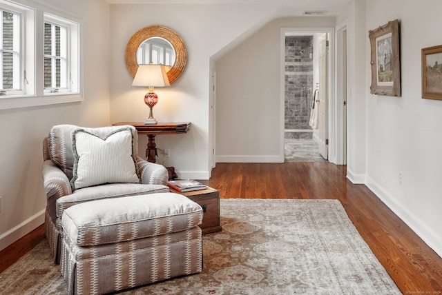 living area featuring visible vents, baseboards, and wood finished floors