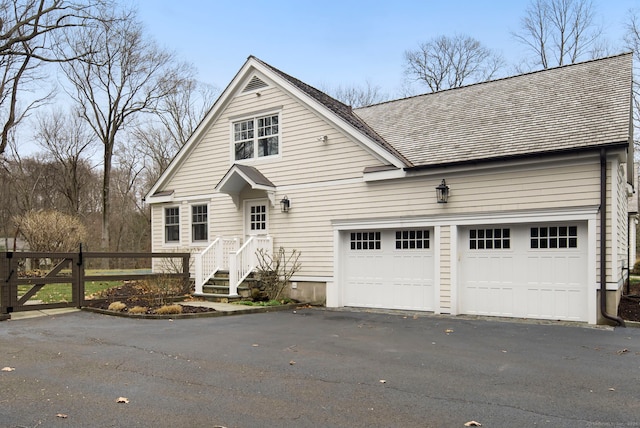 view of front of property featuring a garage, fence, and aphalt driveway