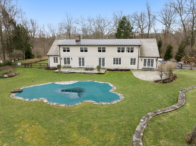 rear view of property with metal roof, a chimney, a deck, and french doors