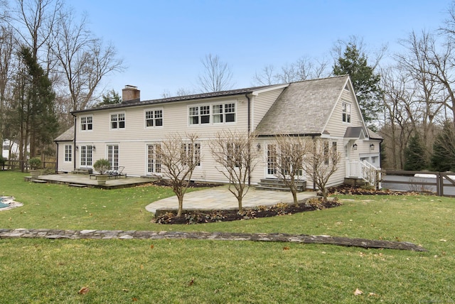 back of house featuring a deck, a patio, fence, a yard, and a chimney