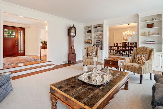 living room with visible vents, baseboards, ornamental molding, an inviting chandelier, and built in shelves