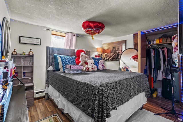 bedroom with a textured ceiling, a closet, baseboard heating, and wood finished floors