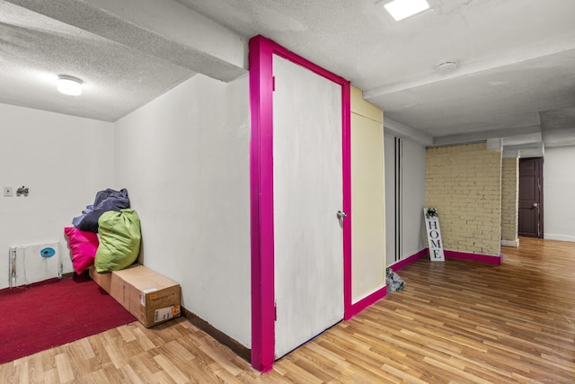 interior space featuring baseboards, a textured ceiling, and wood finished floors