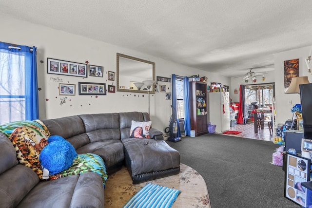 carpeted living room with a ceiling fan and a textured ceiling