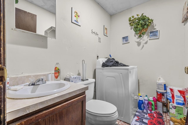 half bathroom with toilet, vanity, and washer / dryer