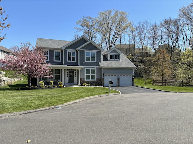 view of front of property featuring an attached garage, fence, stone siding, driveway, and a front lawn